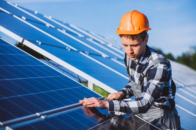 Montator care prinde un panou fotovoltaic pe structura de aluminiu, sub cer senin